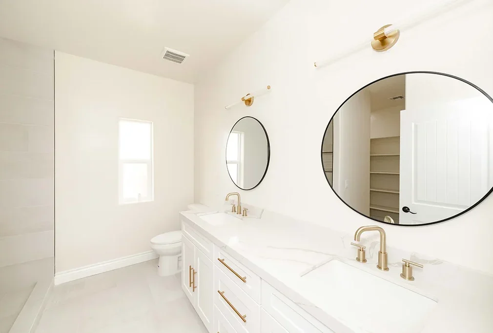 Double vanity bathroom remodel in Kingman AZ with round mirrors and quartz counters carried out by JSE: General Contractors in Kingman